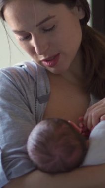 Beyaz, orta yaşlı, elleri tutan ve bebeğini emziren bir kadın. Annelik, masumiyet ve bağlantı kavramı. Dikey video.