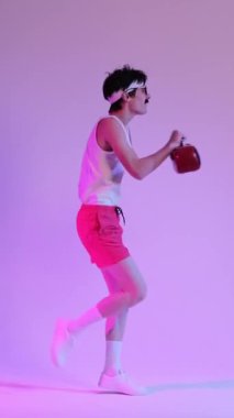 Neşeli, genç, beyaz bir adam mor arka planda dinamik 90 'lar dansı yapıyor. Disko dansı kavramı. Dikey video.