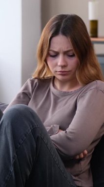 Evde depresyon ve melankolik genç, beyaz bir kadın var. Hayal kırıklığı, umutsuzluk ve yalnızlık kavramı. Dikey video.