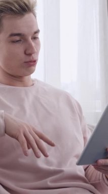 Mutlu adam bir video görüşmesine katılıyor ve evde tablet bilgisayar kullanarak arkadaşlarıyla konuşuyor. Boş zamanlarında internet iletişiminin ve sosyalleşmenin tadını çıkarıyor. Dikey video.