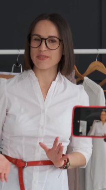 Kadın blogcu internetteki bir toplulukla etkileşime giriyor ya da sosyal medya için bir moda blogu kaydediyor, gardıroptan bir seyirciyle iletişim kuruyor, dijital içerik yaratıyor. Dikey video.