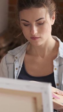 Neşeli sanatçı bir sanat stüdyosundaki tuvale resim yaparak zaman harcıyor, ilham alıyor ve yaratıcılığını ifade ediyor. Dikey video.