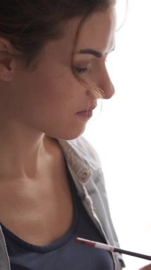 Bir atölyede resim yapan sanatçı, sanat terapisine katılan ya da yaratıcı ve rahatlatıcı bir atmosferde vakit geçiren. Dikey video.