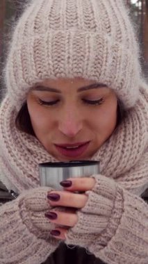 Sıcak çay içen olumlu bir kadının portresi kış ormanlarını keşfederken dışarıda mutluluk ve rahatlama yayıyor. Dikey video.