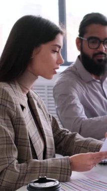 Kafkasyalı iş kadını ve Arap işadamı, büroda çalışan evraklarla birlikte iş planı geliştiriyorlar. Dikey video.