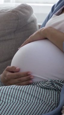 Hamile bir kadının karnına nazikçe dokunması ebeveynlik ve doğum beklentisini ifade ediyor. Sakin annelik ve bakım. Dikey video.