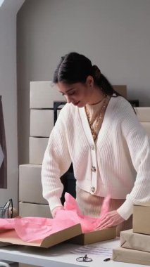 Arkadaş canlısı Kafkasyalı genç yetişkin iş kadını çevrimiçi mağaza deposunda müşterileri için paket ya da sipariş hazırlıyor. Yönetim ve nakliye kavramı. Dikey video.