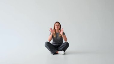 Dost canlısı, beyaz arka planda oturan, Lotus pozunda yoga meditasyonu yapan beyaz, yetişkin bir kadın. Zen, barış, sükunet, tefekkür konsepti.