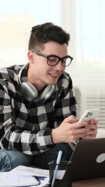 Neşeli Kafkasyalı genç adam para yağdırıyor ve evde refahı veya zaferi kutluyor. Servet ve sermaye kavramı. Dikey video.