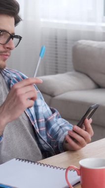 Kafası karışmış bir serbest çalışan ya da yönetici akıllı telefon kullanarak internet üzerinden çalışıyor. İşine ve muhasebesine odaklanmış vazifeleri yönetir ve uzaktan iletişim kurar. Dikey video.