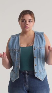 Bilmece gibi bir kadın beyaz bir arkaplanda kollarını açar, şüphe, reddedilme ya da sorgu jesti ile bir ikilemi ifade eder. Dikey video.