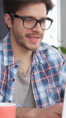 Neşeli uzaktan kumandalı işçi evden çalışırken bir iş stratejisi geliştirmek için dizüstü bilgisayar kullanıyor. Üretken ve motive. Dikey video.