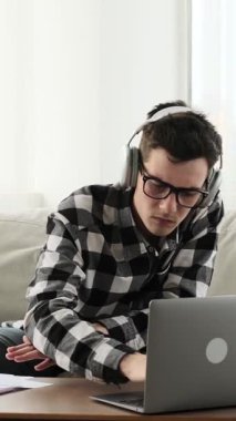 Neşeli Kafkasyalı genç yetişkin adam evde dinleniyor ve akıllı telefon kullanarak eğleniyor. Boş zaman kavramı ve rahatlama. Dikey video.