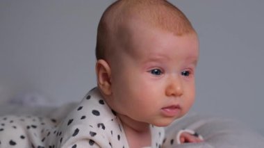 Evde yeni doğmuş meraklı bir bebeğin yakın plan portresi. Bebeklik ve erken öğrenme, çocukluğun başlangıcını masumiyet ve merakla araştırır..