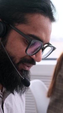 Olumlu Arap erkek müşteri hizmetleri çalışanı ofisteki tüketicilerle uzaktan konuşma ya da diyalog kuruyor. Teknik destek ve tele pazarlama kavramı. Dikey video.