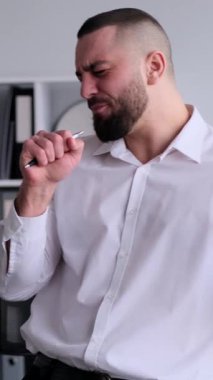 Gülümseyen beyaz erkek orta yaşlı ofis çalışanı müzik eşliğinde dans ediyor ve ofiste şarkı söylüyor ve başarıyı veya zaferi kutluyor. Dikey video.