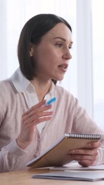 Pozitif serbest çalışan kişi, internet üzerinden yapılan bir video görüşmesine ya da bir müşteriyle ev ofisinde çalışırken buluşmaya katılıyor. Odaklanmış ve profesyonel, internetteki iş görevlerini yönetiyor. Dikey video.