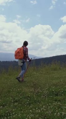Neşeli bir hamile kadın yürüyüşçünün hava manzarası dağlarda, yemyeşil otlaklarda ve ormanlarda yolculuğun tadını çıkarıyor. Doğayla bağlantı. Dikey video.