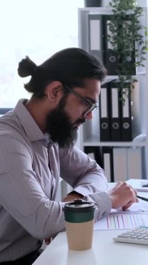 Bütçeyi planlamak ve analiz etmek için ofiste pazarlık yapan ve belgelerle çalışan çok uluslu iş arkadaşları. Dikey video.