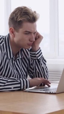 Ofiste dizüstü bilgisayarla çalışan dalgın bir işadamı, bir iş stratejisi geliştirmeye ve etkili bir planlama için kilit verileri analiz etmeye odaklandı. Dikey video.
