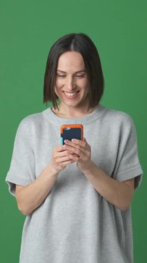 Çevrimiçi eğlence için telefon kullanan olumlu bir kadın, dijital eğlence, internet gezme ve sanal içerikten zevk alıyor. Dikey video.