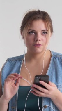 Neşeli bir kadın şarkı söyler, müzik eşliğinde dans eder ve boş zamanlarında telefon kullanır. Mutluluk ve eğlence yayar. Dikey video.