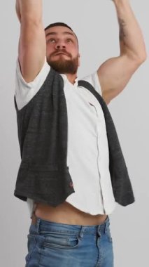 İyi haberleri ve başarıyı beyaz bir arka planda kutlayan ve evet diye bağıran bir adam. İnançsızlık, sevinç ve başarı ve kutlama anındaki heyecan. Dikey video.