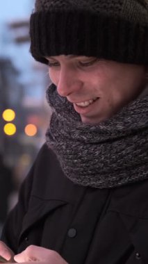 Mutlu adam cep telefonunu online eğlence ve eğlence için kullanır kış aylarında dışarıda dolaşırken, keyifli bir anın tadını çıkarır. Dikey video.