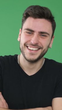 Rahatlamış ve pozitif bir adamın portresi yeşil bir arka planda neşeyle gülüyor. İyi ruh hali olan dost canlısı insanlar. Dikey video.