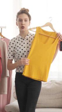 Moda blogcusu bir moda blogu için yayın akışı sunuyor, kıyafetleri gözden geçiriyor ve evden sosyal medyada izleyicilerle iletişim kuruyor. Dikey video.
