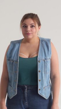 Oyuncu bir kadın, beyaz arka planda hiçbir işaret yokken, mizah anlayışıyla reddedilmeyi ifade eden komik bir ret hareketi gösterir. Dikey video.