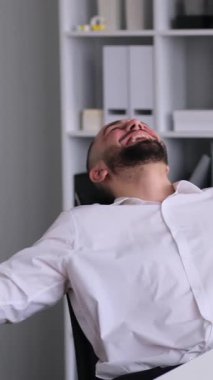 Ofiste çalışırken zaferi kutlayan Kafkasyalı orta yaşlı bir erkek. Başarılı bir anlaşma ve hedef kavramı. Dikey video.
