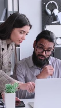 Ofiste toplantı sırasında laptopla çalışan çok uluslu pozitif ofis çalışanları. Takım çalışması ve işbirliği konsepti. Dikey video.