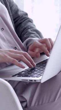 Kadın öğrenci evde bir sandalyeye oturmuş, bilgisayarla e-öğrenmeye odaklanmış. Çevrimiçi eğitim, internet bağlantısı ve modern öğrenme yöntemleri. Dikey video.