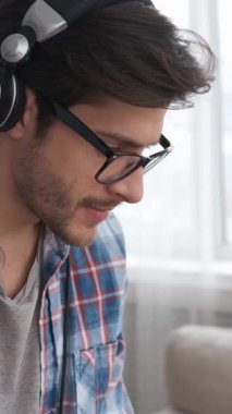 Olumlu adam DJ evde mikser kullanarak müzik çalmaktan hoşlanıyor. Yaratıcı sürecinde eğlence ve keyif buluyor. Dikey video.