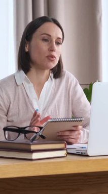 Happy ofis çalışanlarından biri internetten video görüşmesi ya da internet görüşmesi için laptop kullanıyor. Üretken ve meşgul, profesyonel sorumlulukları coşkuyla yönetiyor. Dikey video.