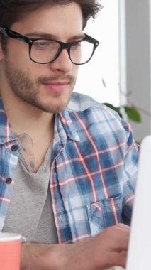 Finans, girişim ya da iş projesiyle uğraşırken evde dizüstü bilgisayarla çalışan neşeli bir işçi. Meşgul ve odaklanmış durumda. Dikey video.