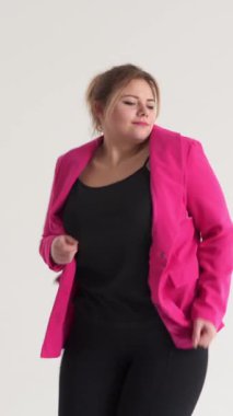 Beyaz arka planda ritmik müzik eşliğinde dans eden, pozitif ruh hali, pozitif ruh hali ve parti enerjisi ifade eden, artı boyut beyaz kadın. Dikey video.