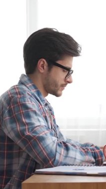 Konsantre olmuş serbest çalışan bir bilgisayar kullanarak internet üzerinde çalışıyor. İşine, muhasebe ve gelişime odaklanmış vazifeleri verimli bir şekilde yönetir. Dikey video.