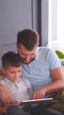 Çocuklu mutlu bir aile evdeki kanepede birlikte vakit geçirir, eğlenir ve eğlenir. Dikey video.
