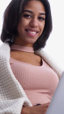 Neşeli bir Afro-Amerikalı kadının portresi evde online eğlence, teknoloji ve rahatlama için dizüstü bilgisayar kullanıyor. Dikey video.