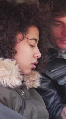 Neşeli çift açık havada bir otomobilde birlikte oturur, telefonu kullanarak online navigasyon için macera mekanı bulurlar. Dikey video.