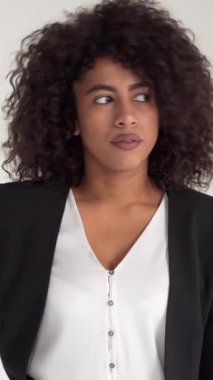 Beyaz bir arka planda geç kalmış birini beklerken, stresli ve sinirli Afrikalı Amerikalı serbest çalışan kol saatine bakıyor. Dikey video.