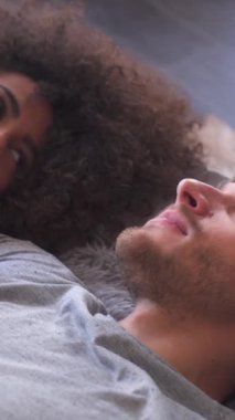 Neşeli sevgili evde dinleniyor. Sıcak ve neşe dolu bir ortamda aşkla sohbetin ve emekliliğin tadını çıkarmak. Dikey video.