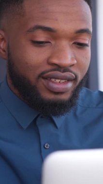 Dost canlısı Afrikalı Amerikalı öğrenci evde bilgisayarla e-öğrenim görüyor, online iletişim ve eğitime odaklanıyor. Konsantrasyon ve dostluk. Dikey video.