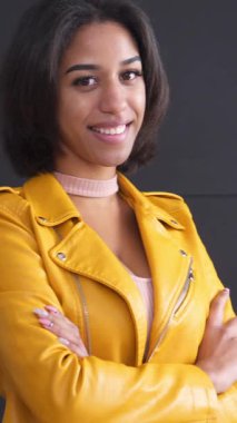 Siyah arka plan, kişilik ve sıcaklıkla kameraya bakan güler yüzlü ve dost canlısı bir Afrikalı Amerikalı kadının portresi. Dikey video.