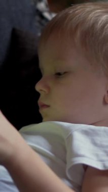 Neşeli hamile anne ve oğlu evde eğlenmek ve eğlenmek için birlikte mutlu anları paylaşmak için bir tablet kullanıyorlar. Dikey video.