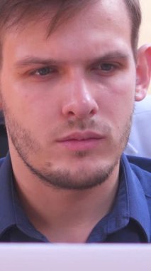 Ofiste dizüstü bilgisayarla çalışan dalgın bir serbest çalışan, iş planları ya da açıklamalar yapan biri. Odaklanma, bağımsızlık ve modern çalışma kültürü. Dikey video.