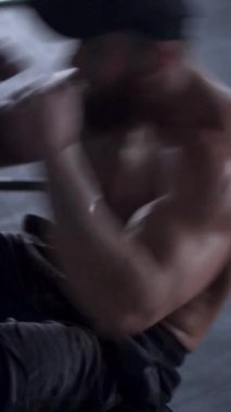 Beden eğitimi sırasında terli ve güçlü bir adam yerde karın kası egzersizi yapıyor. Dayanıklılık, atletizm ve kas zindeliği. Dikey video.