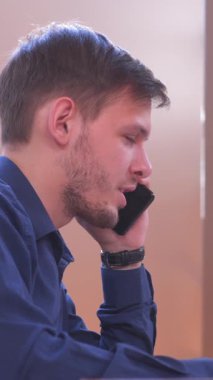 Konsantre çalışan bir ofiste çalışırken bir müşteriyi arar ya da onunla konuşur. Profesyonellik, iletişim ve odaklanma. Dikey video.